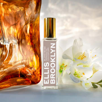 Blond Musk Fragrance Oil 15ml next to block of amber and white flowers against white backdrop.