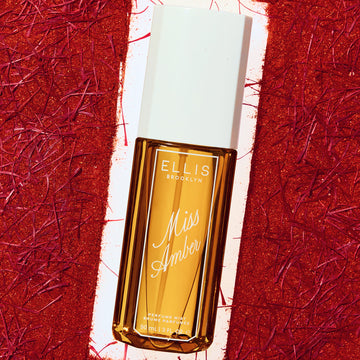 90mL Miss Amber Perfume Mist bottle framed by a red textured backdrop.