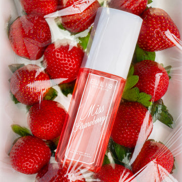 MISS STRAWBERRY Perfume Mist 90ml lays on strawberries on white surface all covered by clear plastic
