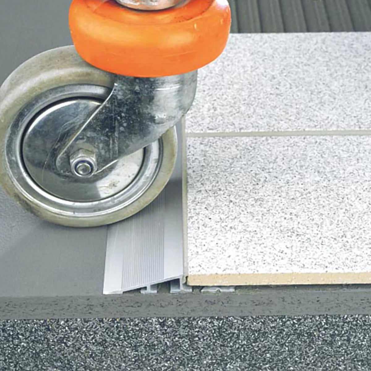 Ambientebild einer Rolle, die über das Höhenausgleichsprofil aus Aluminium mit breiter, rutschfester Oberfläche fährt