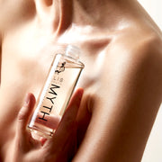 Modèle tenant l'huile corporelle parfumée spectaculaire Myth 95 ml sans bouchon, près de la clavicule, sur fond blanc.