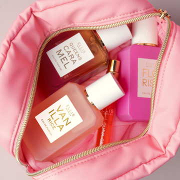 Trousse cosmétique rose avec fermeture éclair dorée ouverte et remplie de QUEENS CARAMEL Eau de Parfum 50ml, FLORIST Eau de Parfum 50ml, VANILLA RICE Eau de Parfum 50ml, et GUAVA GRANITA Eau de Parfum 50ml sur fond gris
